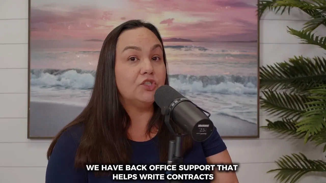Woman speaking into a microphone with subtitle 'We have back office support that helps write contracts' and beach artwork behind her