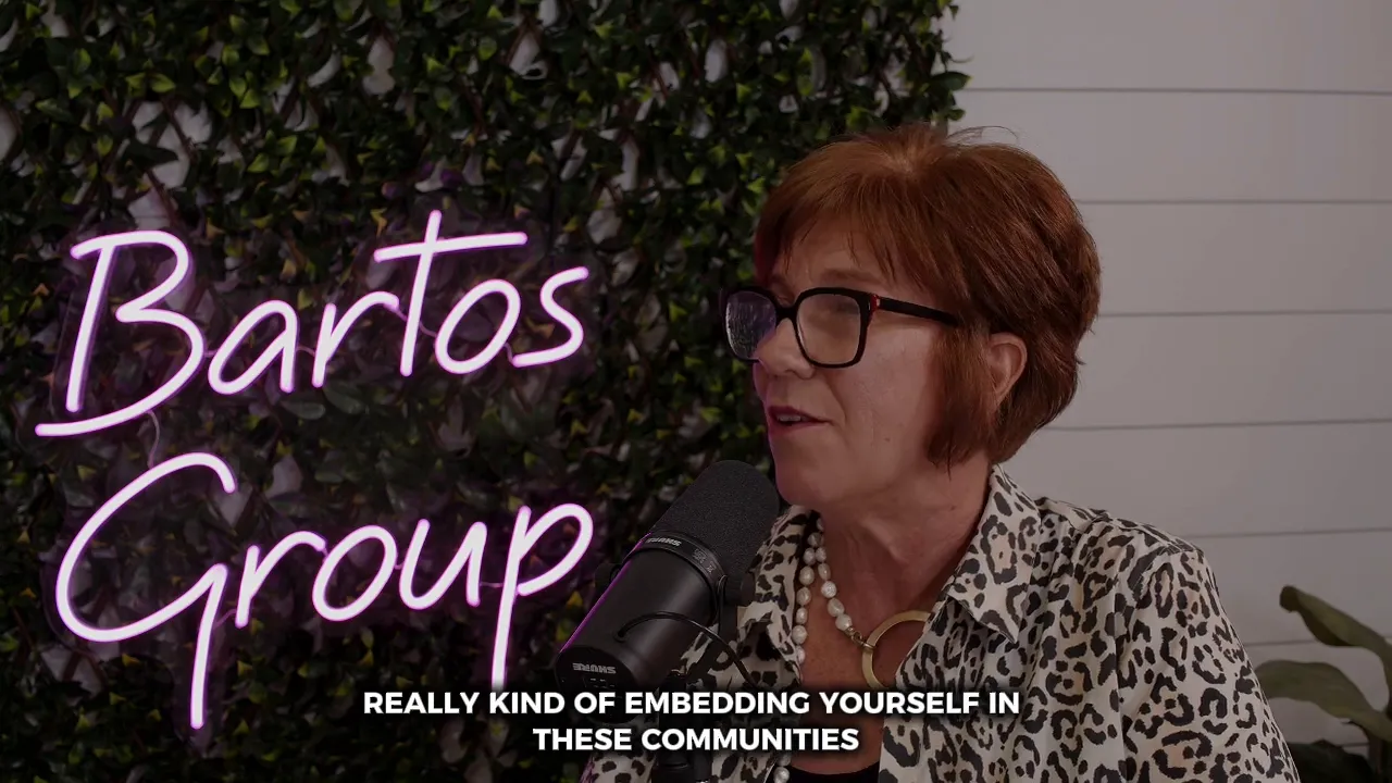 Host speaking into microphone with framed seascape and plant in background